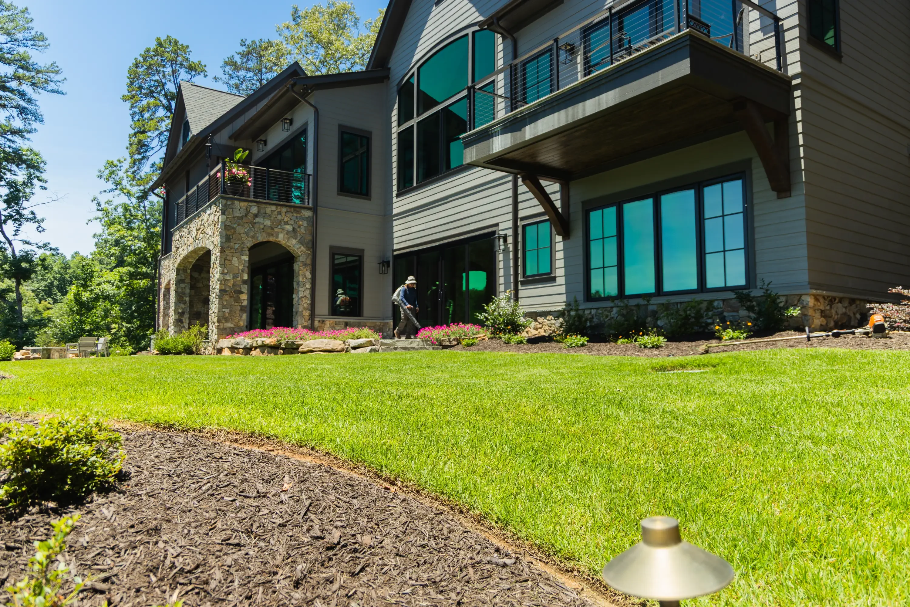 Modern home with newly landscaped front yard, pink flowers, mulch beds, and manicured lawn